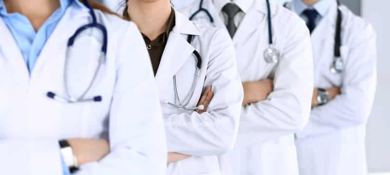 Groupe de médecins en blouses blanches avec stéthoscopes, bras croisés, une équipe médicale unie.